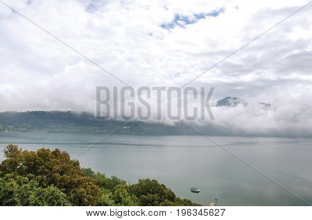 View of the slopes, forests and houses of Lake Albano on a cloudy and foggy day. Albano is a quiet and bucolic countryside region near Rome. Located in the Lazio region, central Italy
