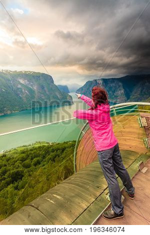 Tourist woman on Stegastein viewpoint enjoying Aurland fjord view in evening time Sogn Og Fjordane Norway