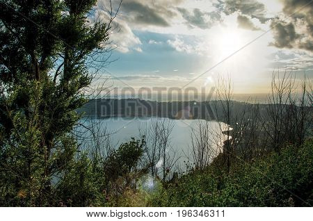 View of the slopes, forests and hills of Lake Albano in a cloudy sunset. Albano is a quiet and bucolic countryside region near Rome. Located in the Lazio region, central Italy. Retouched photo