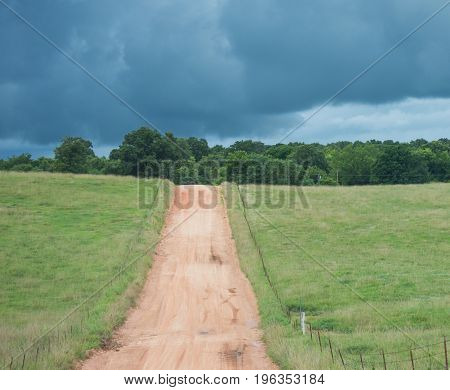 A lonely dirt road and an ominous dark sky gives the sense of mystery as to what may await just over the hillside.
