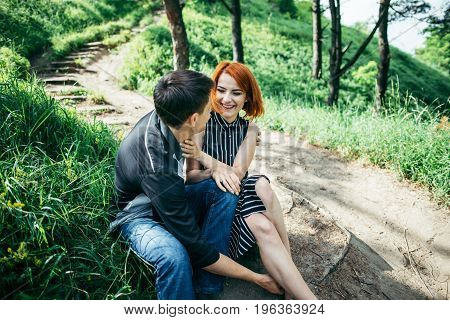 portrait of beautiful young pair in a park sitting on the ground