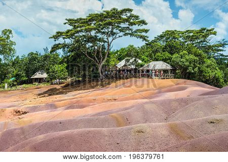 Chamarel Mauritius - December 26 2015: People watching for main sight of Mauritius - Seven Coloured Earth in Mauritius Chamarel nature reserve. Green forest behind and blue cloudy sky.
