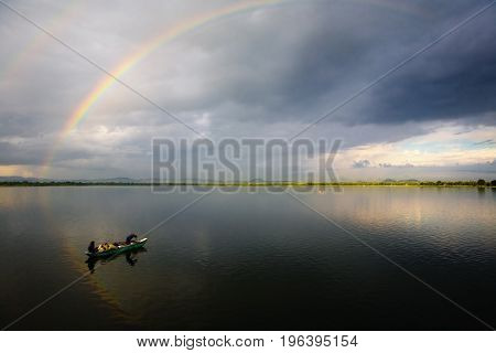 Pollonaruwa Sri Lanka December 20 2015: At dawn Sri Lankan fishermen in a boat on the lake. Above the lake is a rainbow.