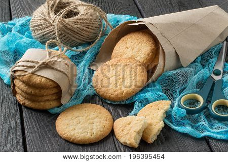 Delicious homemade cookies with onion sesame and spices in paper bag on table with blue gauze napkin as well as a twine for packing
