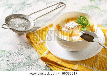 Delicious creamy apricot dessert in white cup on yellow napkin. Sieve with powdered sugar. Summer desserts with fruits. Dietary and healthy food