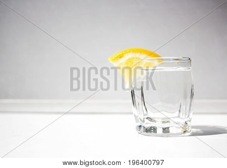 A glass of alcohol with a lemon for a snack