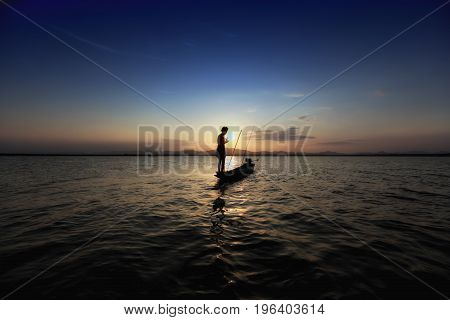 Silhouette Fisherman And Boat In River On During Sunset,thailand