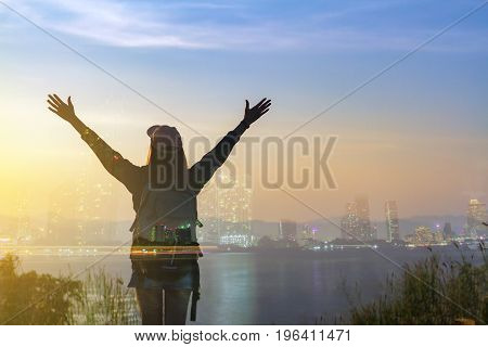 Double exposure Freedom traveler woman standing with raised arms and enjoying a beautiful nature and cheering young woman backpacker at sunrise seaside mountain peak
