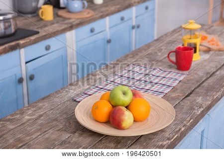 View on the wooden table at kitchen with fruit and teaspot on it. Picture of cuisine with table on front view.