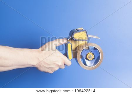 Man holding an industrial tape dispenser on blue