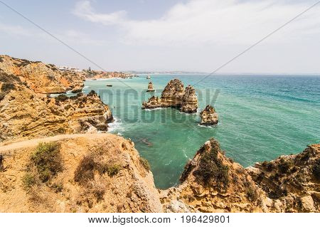 Travel To Stunning Rocks Cliffs With Seas Caves On Sandy Camilo Beach In Colorful Sunny Blue Sky