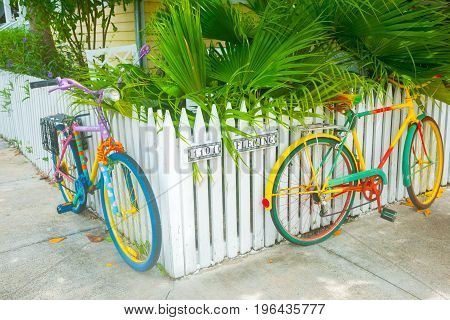 Key West, USA - June 26, 2012; Two brightly painted bicycles leaning on picket fence on residential street corner