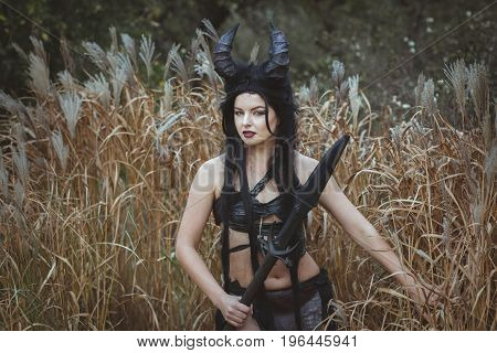 Girl shaman with horns stands in the thickets