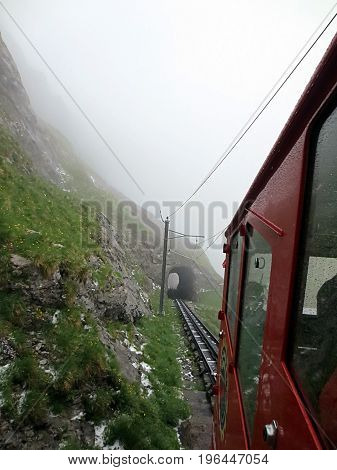 red trolley going up Swiss alps in fog
