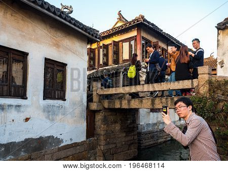 Suzhou, China - Nov 5, 2016: Visitors gather at the stone bridge at the historic Zhouzhuang Water Town. A famous Chinese movie was filmed utilizing this bridge.