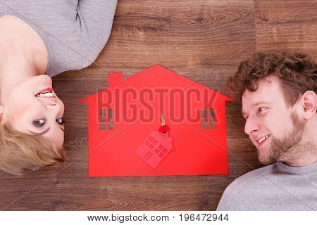 Housing marriage family security future finances mortgage concept. Just married lying on floor. Young man and woman next to home symbol with keyring.