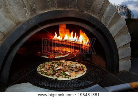 pizza prepares in old stove near fire