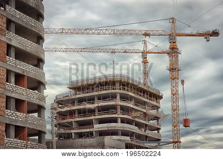 Industrial construction close-up. Construction cranes against background of concrete walls of new buildings. Concept of construction. Construction site.