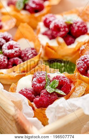 Phyllo cups with Mascarpone cheese  filling topped with fresh raspberries and mint, delicious dessert