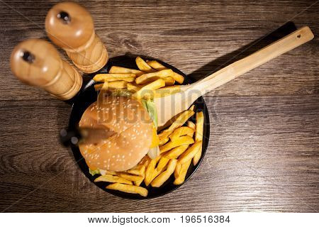 Classic home made cheesburgers on black plate and background next to fries. Fast food. Unhealthy snack