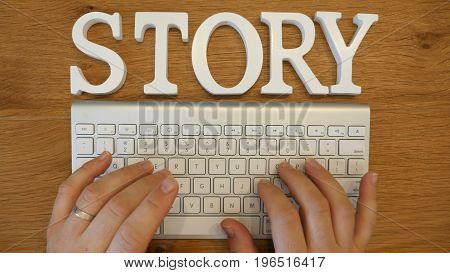 Story concept with hands typing on a white computer keyboard conceptual of journalism and reporting or of an author and writer