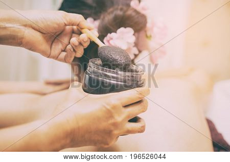 Spa Therapist is putting Charcoal scrub on a woman's back