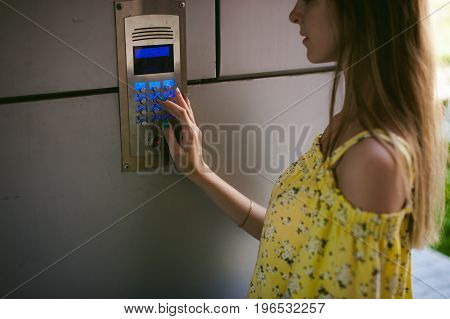 Woman Dials An Apartment Code On An Electronic Doorphone Panel
