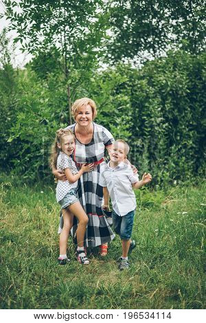 Grandmother playing in the park with grandchildren, siter with brother