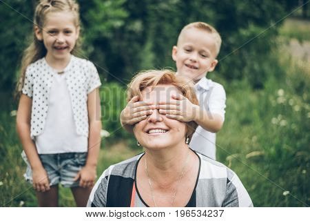 Grandmother playing in the park with grandchildren, siter with brother