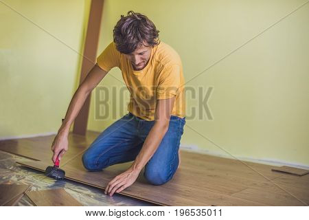 Man Installing New Wooden Laminate Flooring. Infrared Floor Heating System Under Laminate Floor