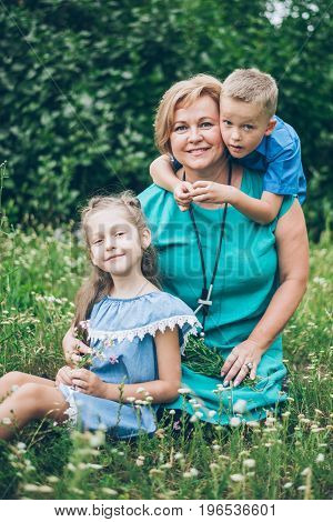 Grandmother playing in the park with grandchildren, siter with brother