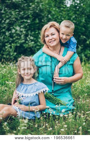 Grandmother playing in the park with grandchildren, siter with brother