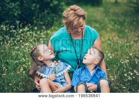 Grandmother playing in the park with grandchildren, siter with brother