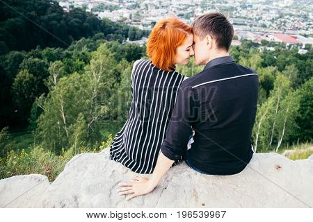 young woman sits with her boyfriend on the peak of the hill with panorama view on the coty