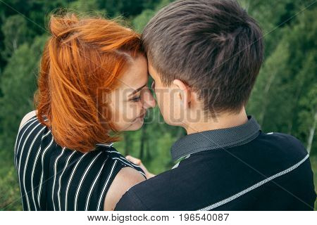 young woman sits with her boyfriend on the peak of the hill with panorama view on the coty