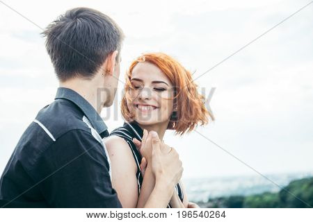 young woman sits with her boyfriend on the peak of the hill with panorama view on the coty