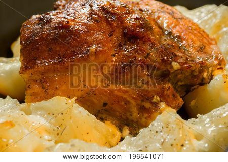 Baked meat with potatoes close. A delicious and hearty meal. A large fried piece of meat. Cooked hot food.