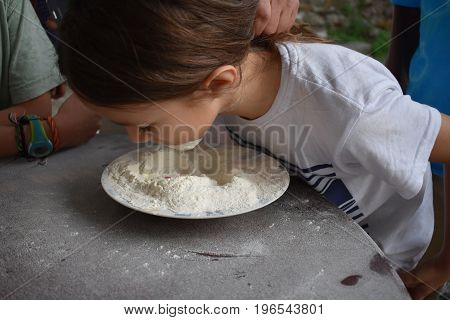 Child plays fetch a prize in a bowl of flour