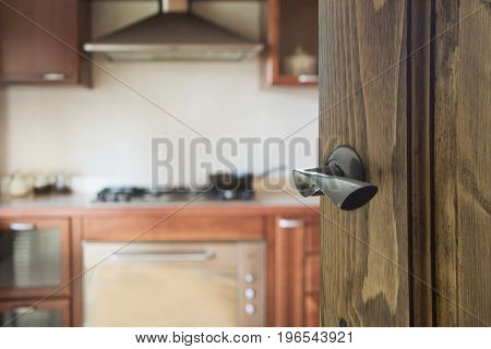 Opened wooden door to kitchen with pan on stove.