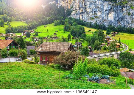 Amazing green fields and famous stunning touristic town with high cliffs in background Lauterbrunnen Bernese Oberland Switzerland Europe