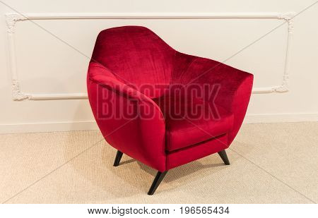 Red armchair on legs against white wall background