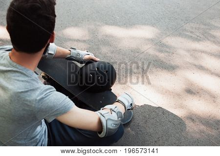 Skateboard halmet and gloves acessrise on unrecognizable skateboarder. Head and hands care protection from injoury. Extreme sport headwear stuff for skater