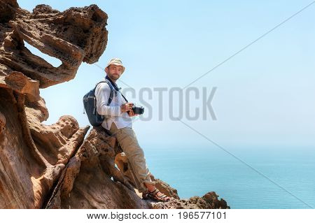 Hormuz Island Hormozgan Province southern Iran traveller with camera sits on the edge of a cliff.