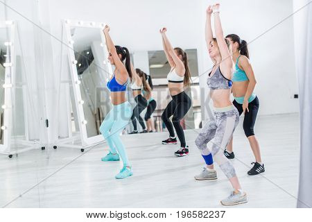 Young female dancers wearing sportswear practicing a new dance move in modern studio.