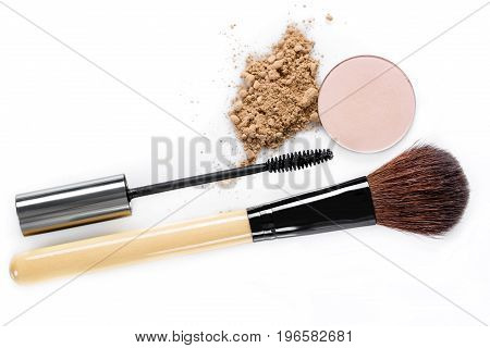 Mascara, beige powder for face, eye shadow and makeup brush on the white background. Natural makeup