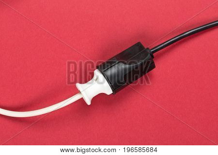 Connected white european power cable plug with black connector cable on red background