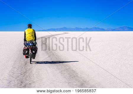 Lonely male cyclist travelling through the biggest salar in the world - Salar de Uyuni in Bolivia