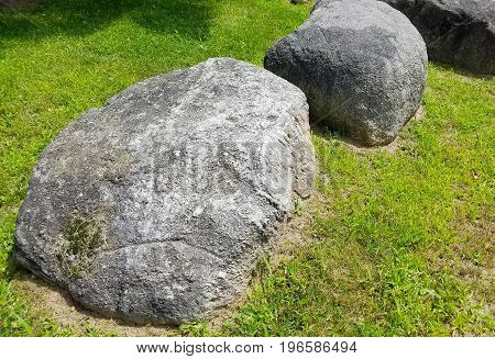 Three big rocks in the sunshine on the grass