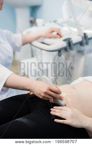 Close-up Of Doctor Moving Ultrasound Probe On Pregnant Woman's Stomach In Hospital.