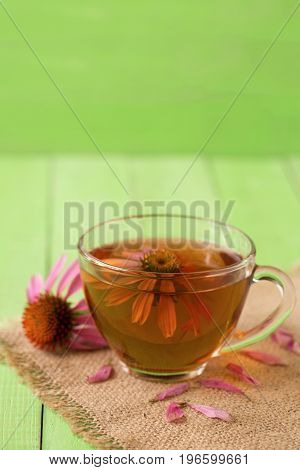 Cup of echinacea tea on green wooden table.